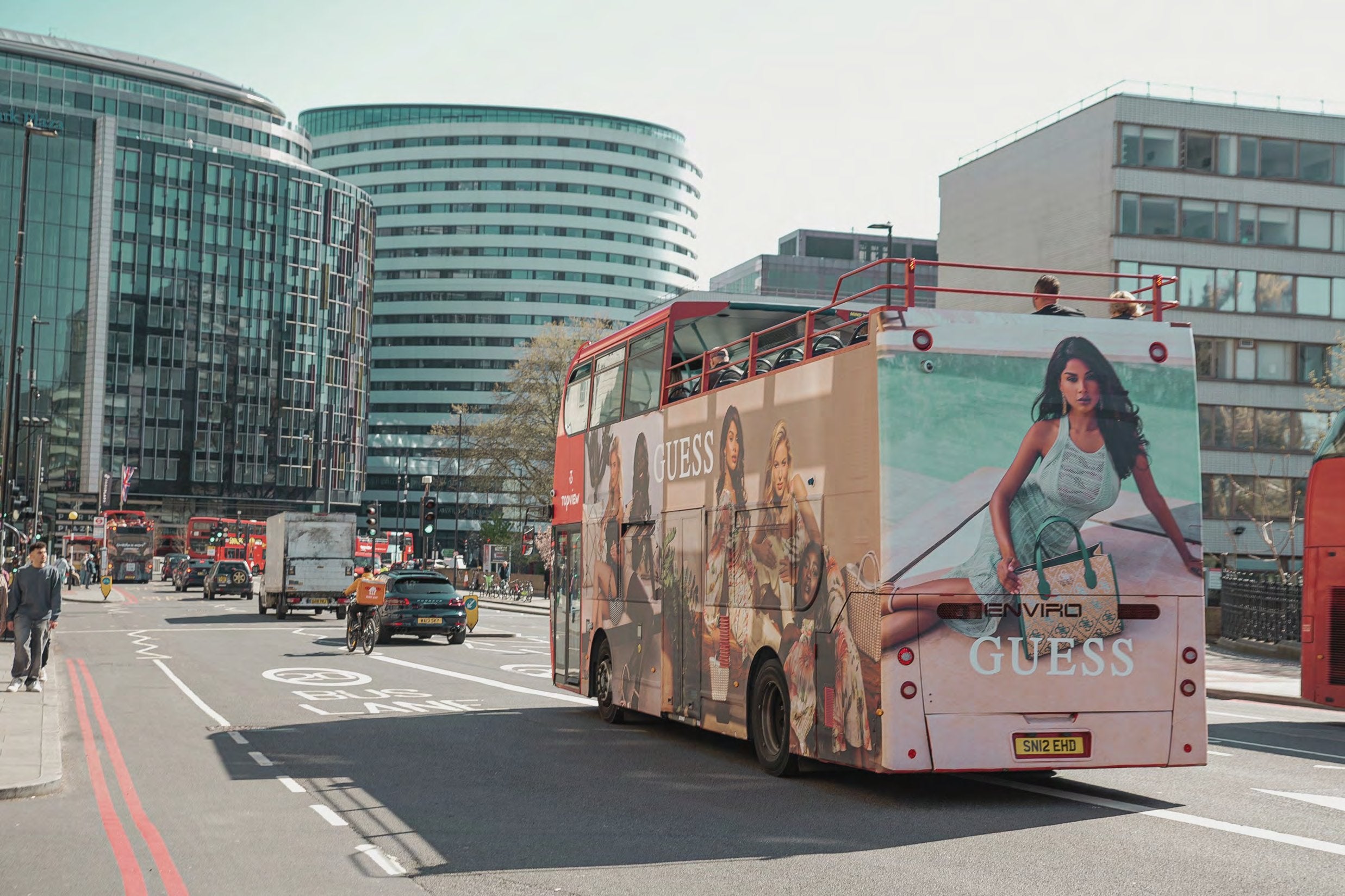 Full-wrap open-top tourist bus travelling through central London